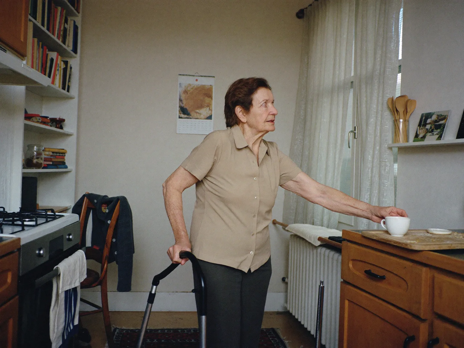 Ältere Frau am Rollator stellt in ihrer Küche eine Tasse ab