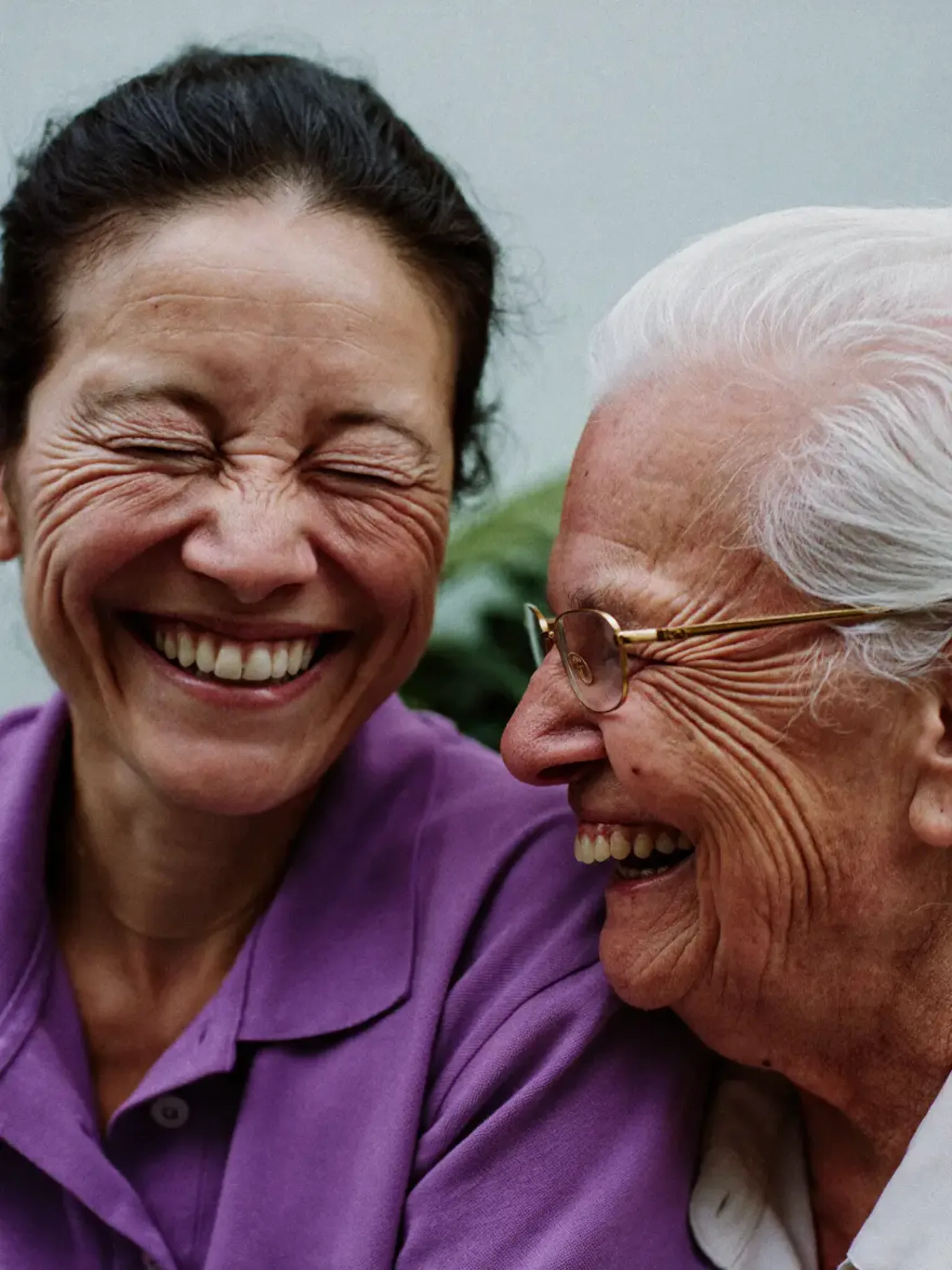 Haushaltshilfe und Seniorin lachen Wange an Wange in Neuweiler