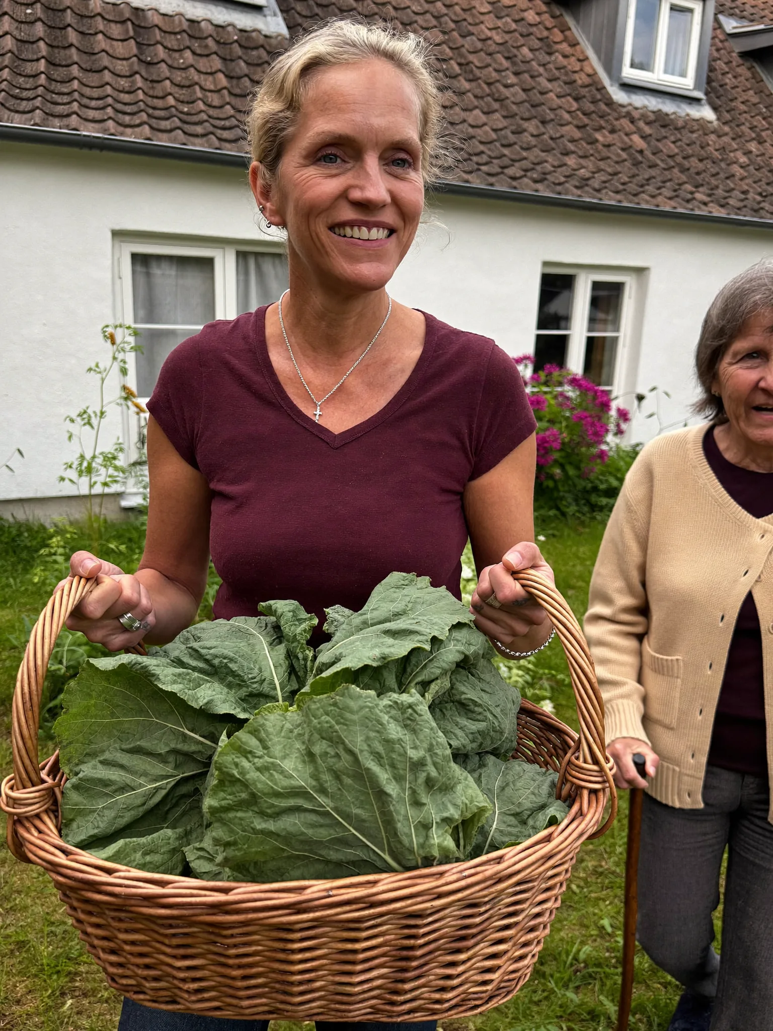 Frau trägt einen Korb mit Gemüse durch den Garten in Simmersfeld